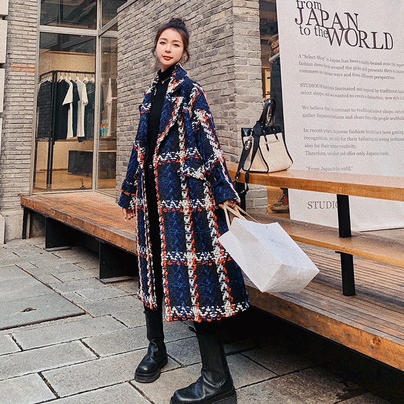 Woman wearing a blue, red, and white plaid woolen mid-length overcoat, styled with a black turtleneck and black pants, showcasing Harajuku fashion.