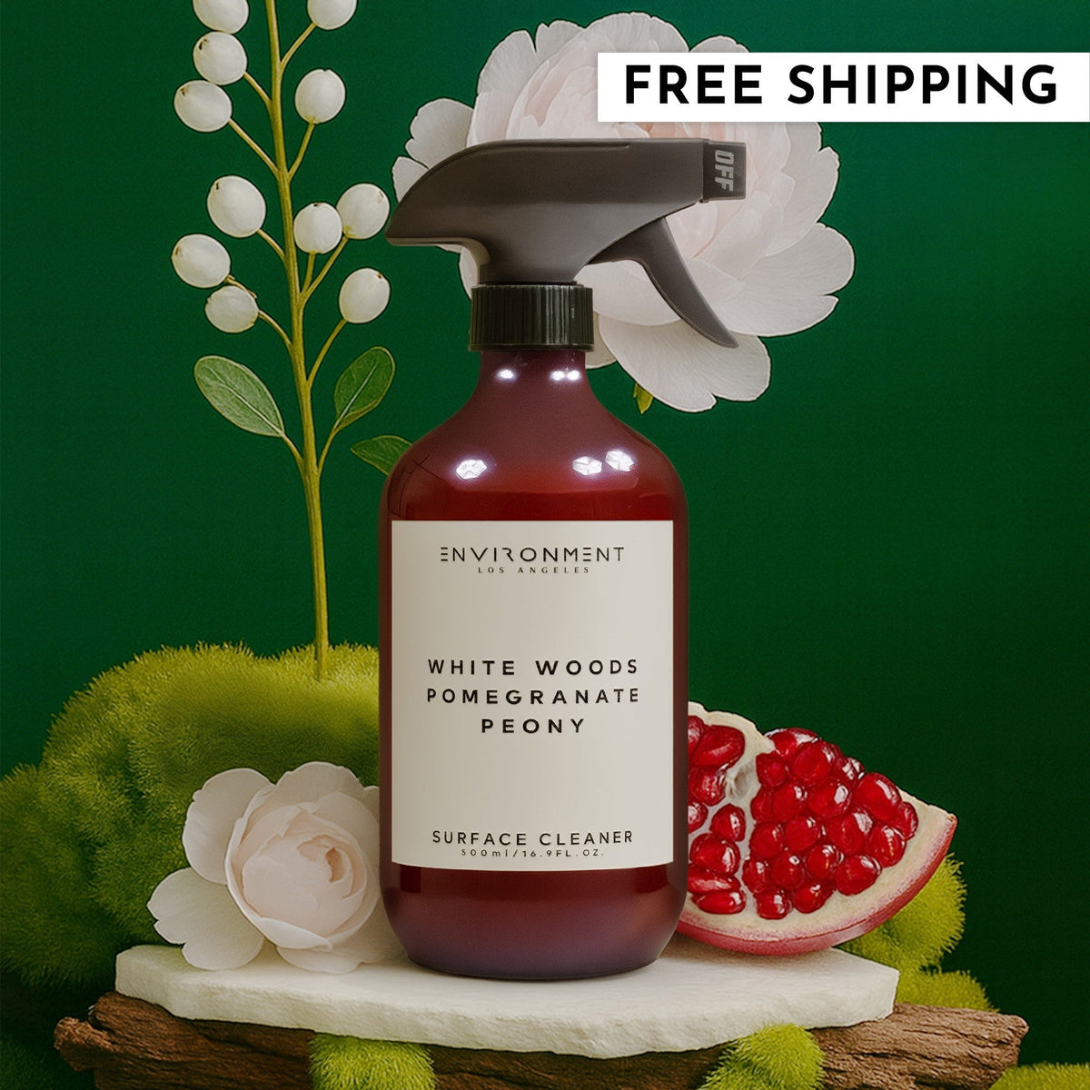 Bottle of White Woods Pomegranate Peony surface cleaner surrounded by natural moss, flowers, and fruit.
