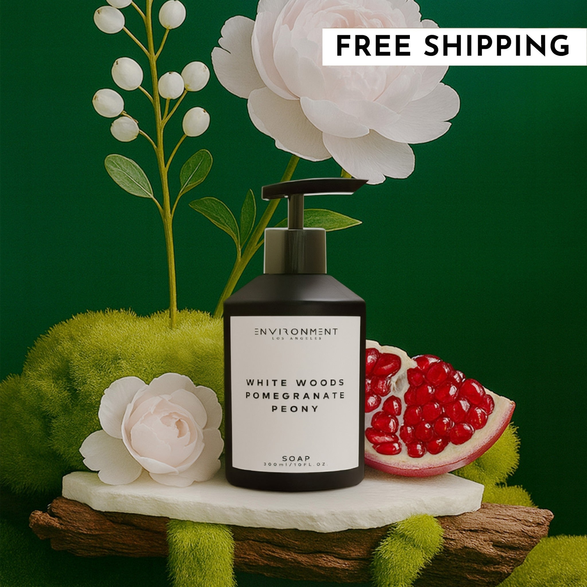 A bottle of White Woods Pomegranate Peony hand soap in a minimalist black bottle displayed in a lush, nature-inspired setting with pomegranate and peony flowers.