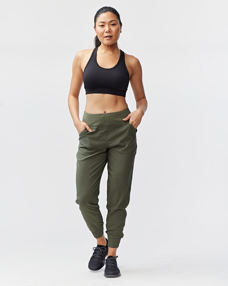 Model wearing a 7/8 length olive green performance jogger with elastic cuffs and a wide waistband.