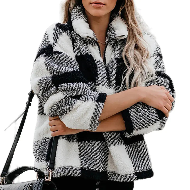 A woman wearing a thick, black and white plaid sherpa-style zip-up jacket with a stand collar.