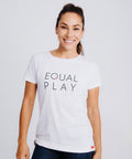 A smiling woman wearing a white short-sleeved crew neck t-shirt with the text Equal Play on the front.