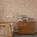 Close up of Heather floral wallpaper featuring a vintage botanical peach and cream pattern in a bedroom setting.