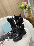 Women's black leather platform combat boots with chunky lug soles and detachable zippered pouches on a light sofa.