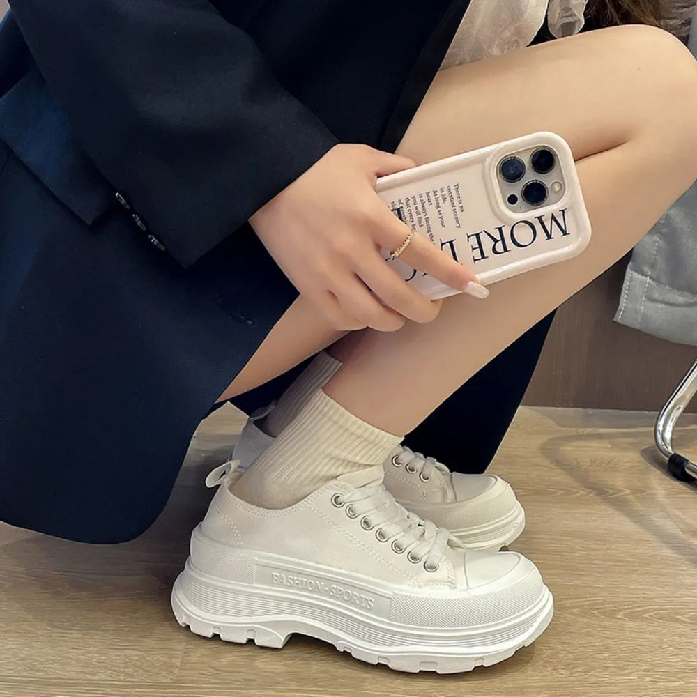 Women wearing stylish lace-up round toe platform sneakers with chunky soles in white canvas