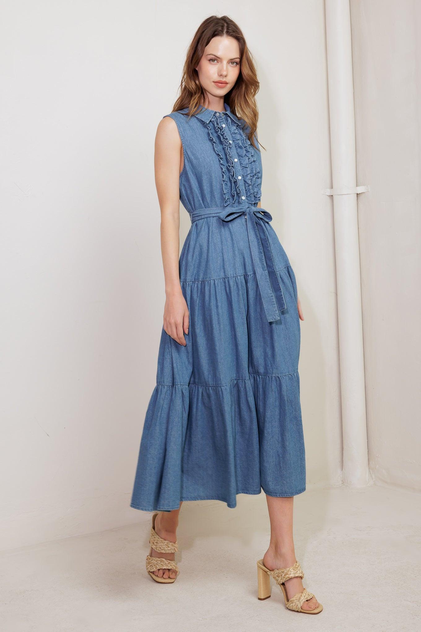 Model wearing a blue washed denim sleeveless midi dress with ruffled front and tie waist