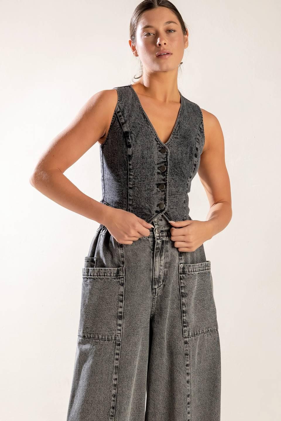 A woman wearing a grey acid wash denim vest with a button-up front and a fitted silhouette.