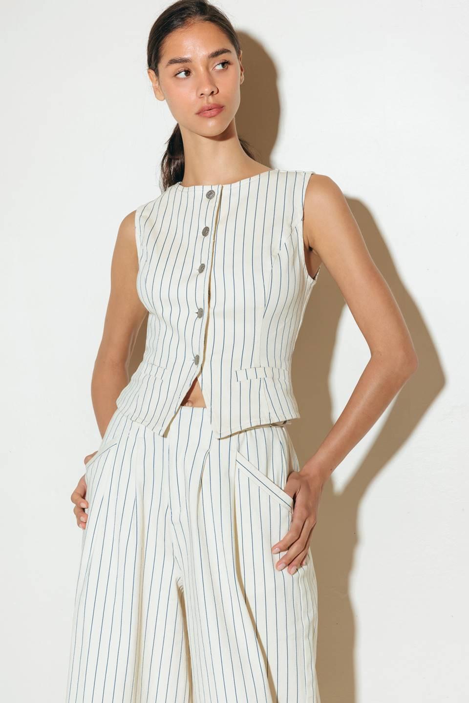 Model wearing a cream-colored woven vest with navy blue vertical stripes and front button closure