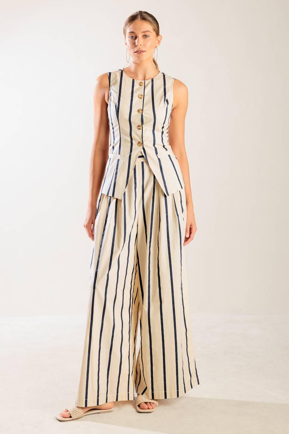 Model wearing a striped cream and navy woven button-down vest with a round neckline.