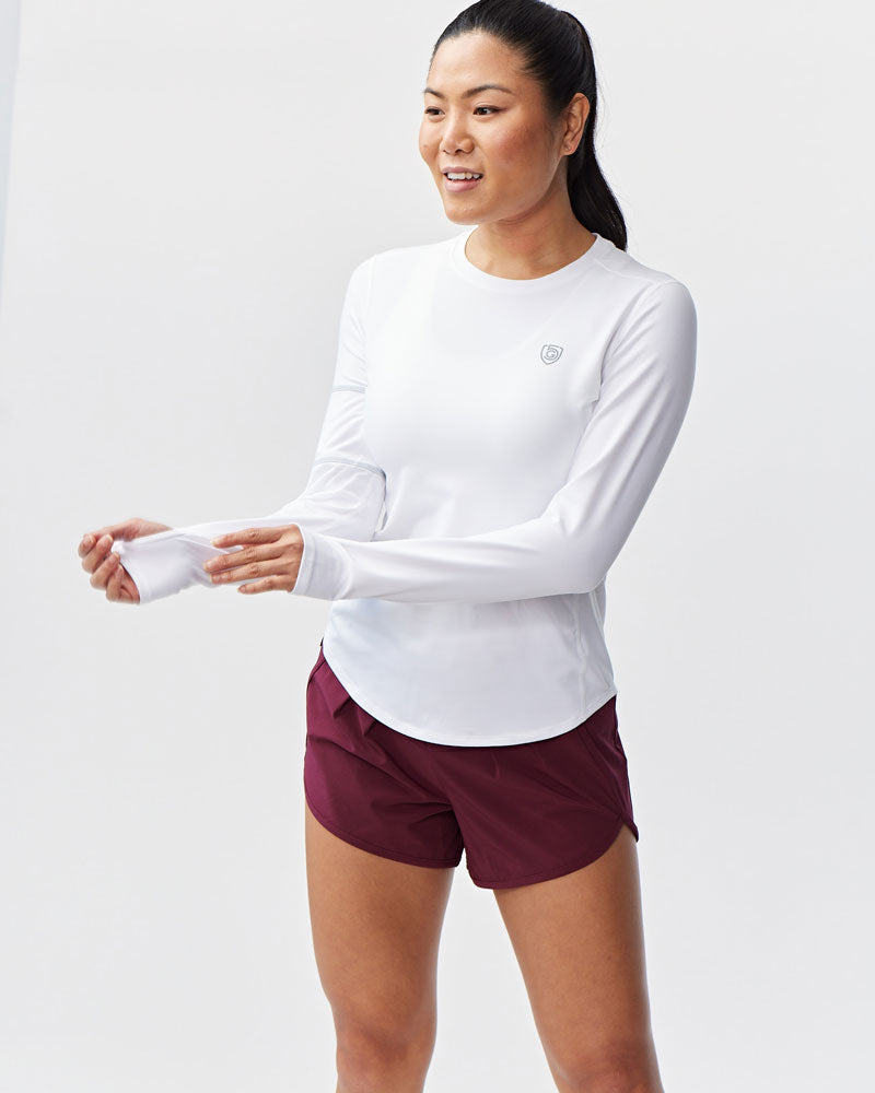 Athlete wearing a white long sleeve athletic shirt with a rounded hem.