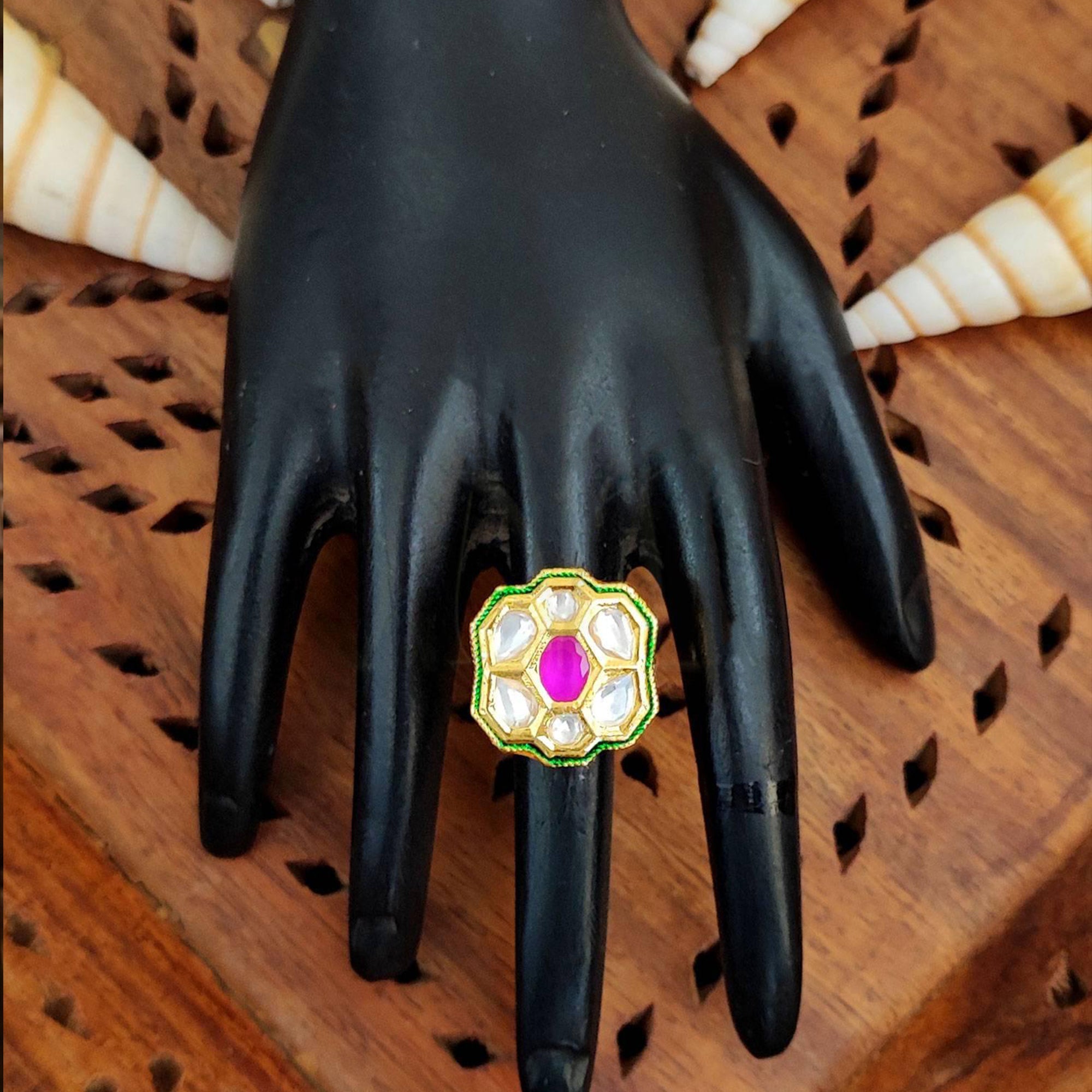 Close-up of a floral Kundan finger ring with multi-colored gemstones and high gold finish on a model hand.