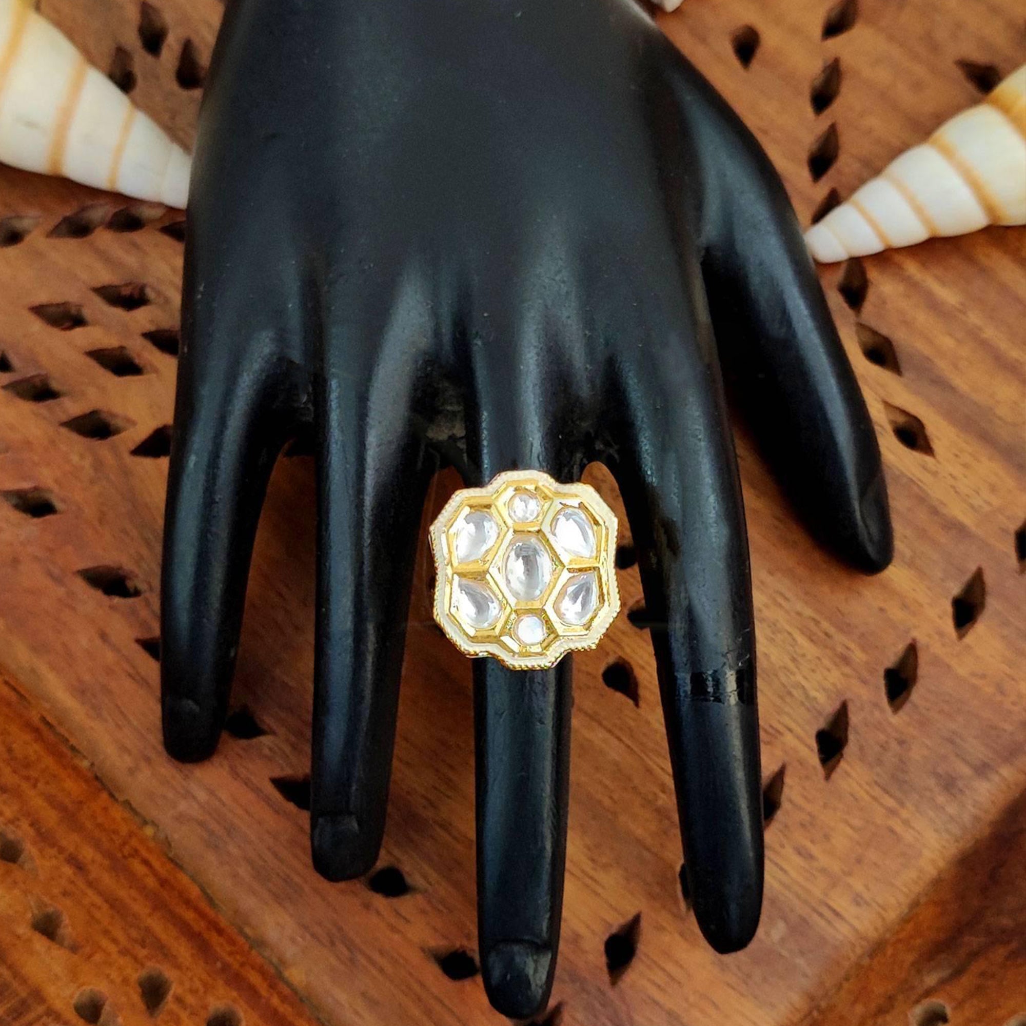 Close-up of a floral Kundan finger ring with multi-colored gemstones and high gold finish on a model hand.