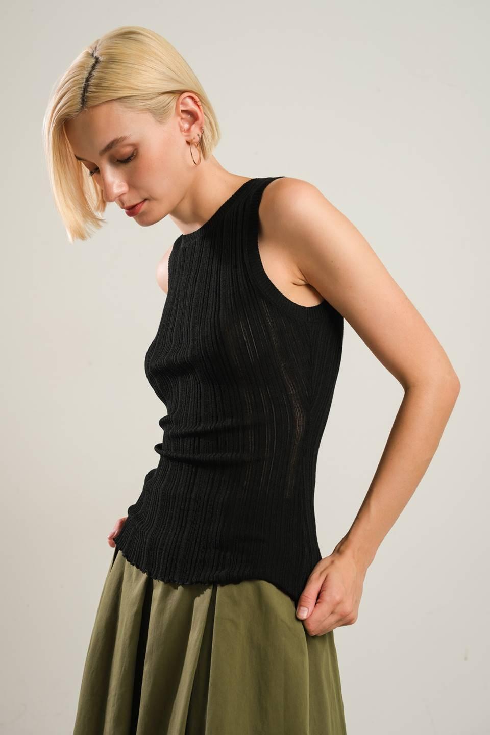 A woman wearing a fitted black ribbed sleeveless sweater top with a round neckline against a neutral background.