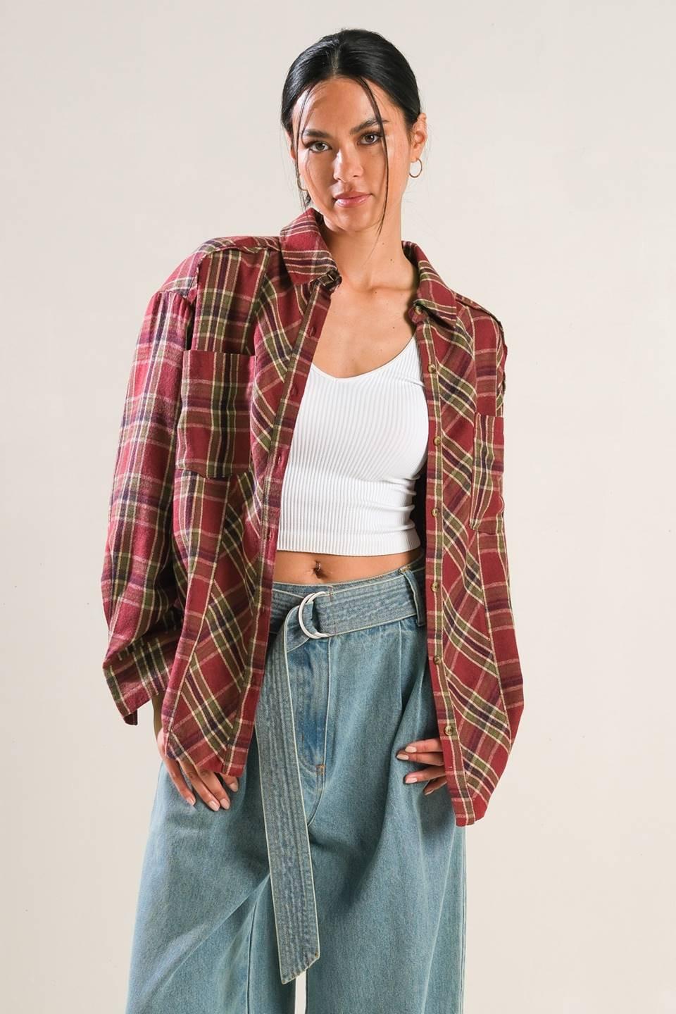 A woman wearing a red and green plaid long sleeve button-down woven top, styled as an open overshirt.