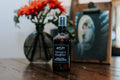 Farmer's Daughter natural room air spray in an amber glass bottle sitting on a rustic wooden table.