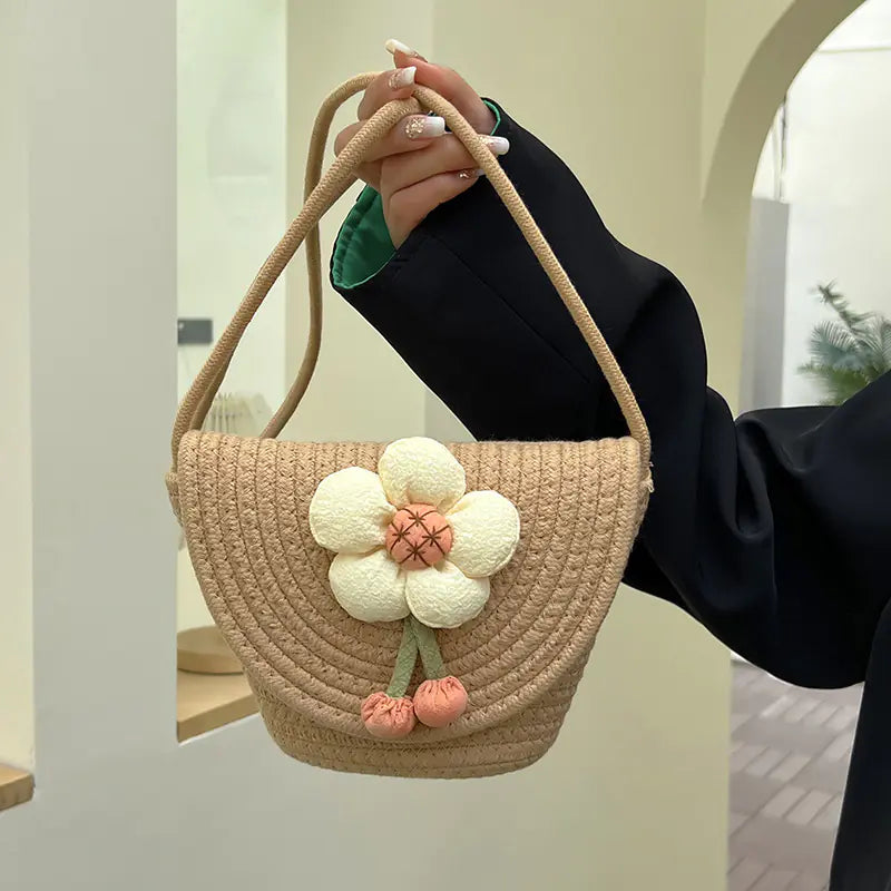 Mini woven messenger bag with a fabric flower applique and cherry charms in khaki color