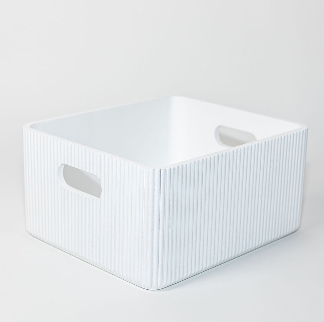 White ribbed wooden storage bin with cutout handles on a clean white background