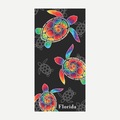 A rectangular beach towel with a black background, featuring colorful tie-dye sea turtle graphics and the text Florida.