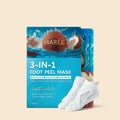 Maree 3-in-1 hydrating foot peel mask packaging next to white moisturizing foot socks