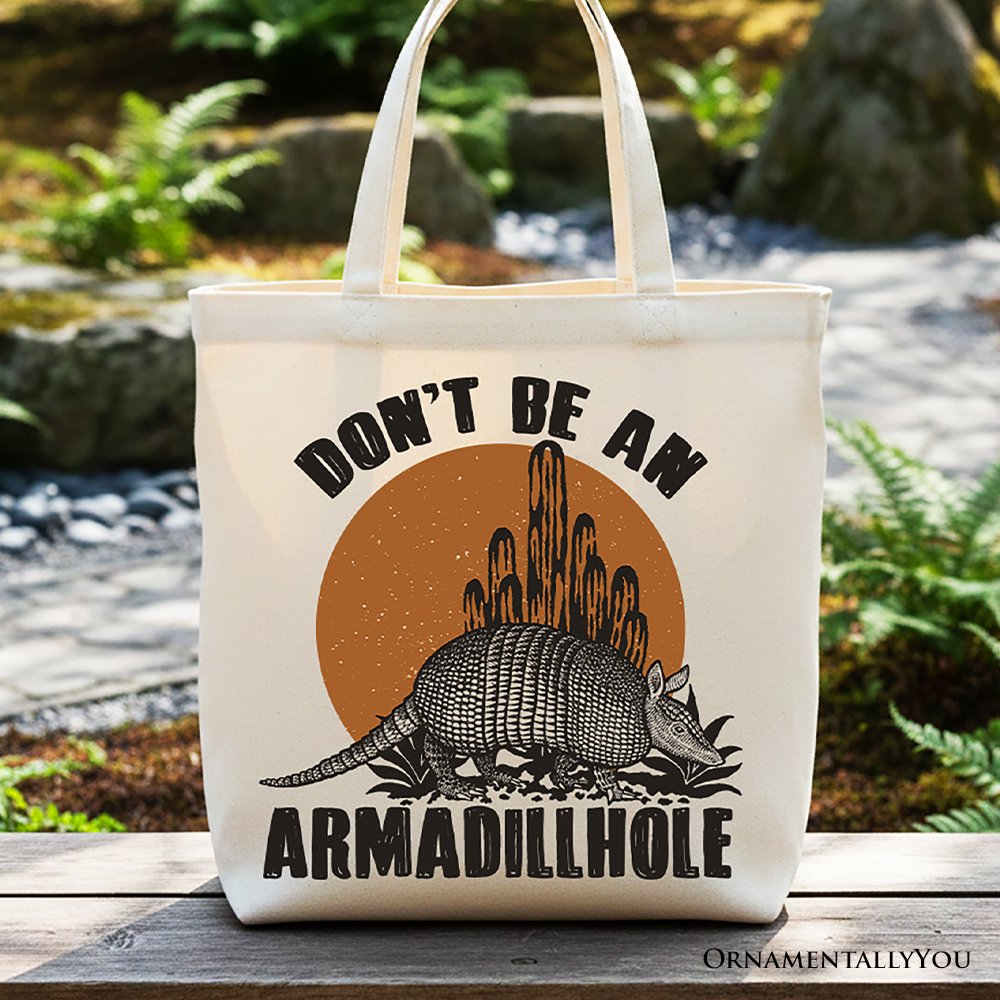 Cream canvas tote bag with 'Don’t Be An Armadillhole' text and armadillo graphic.