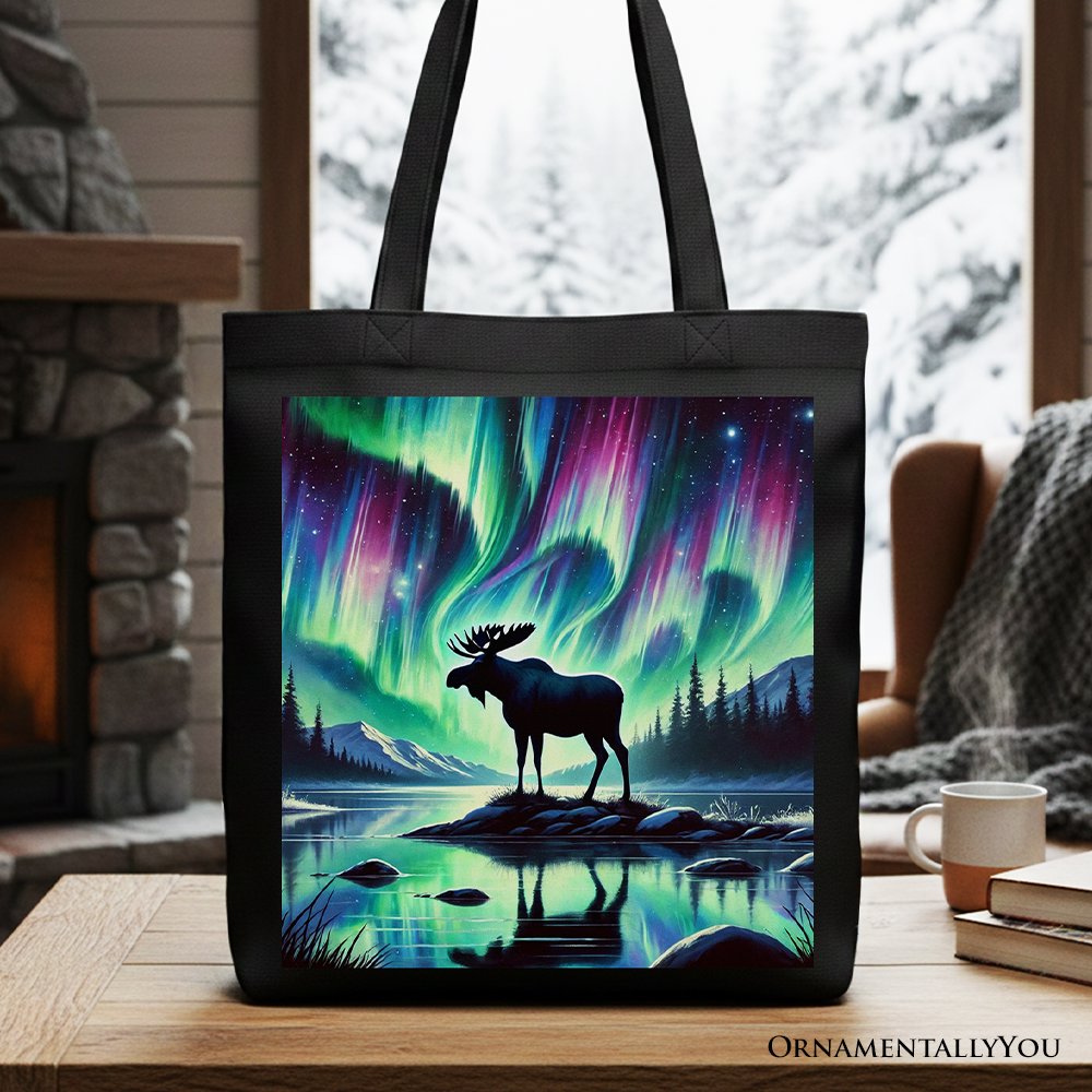 A black cotton canvas tote bag featuring a majestic moose silhouette under colorful Northern Lights artwork.