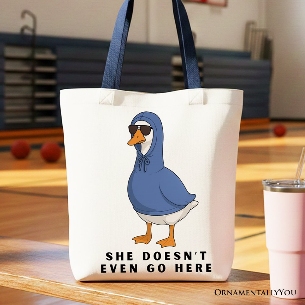 White canvas tote bag featuring 'She Doesn't Even Go Here' text in blue and orange.