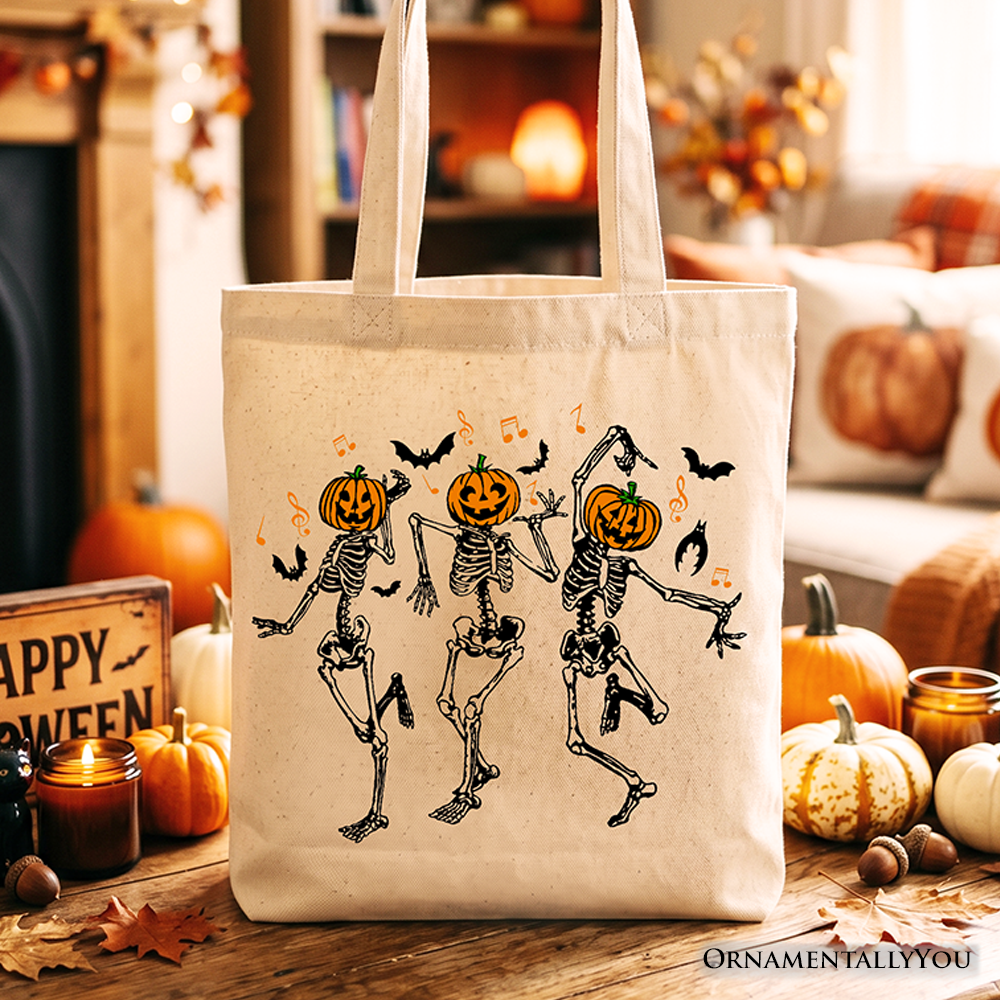 Dancing skeletons with pumpkin heads graphic printed on a beige cotton canvas tote bag.