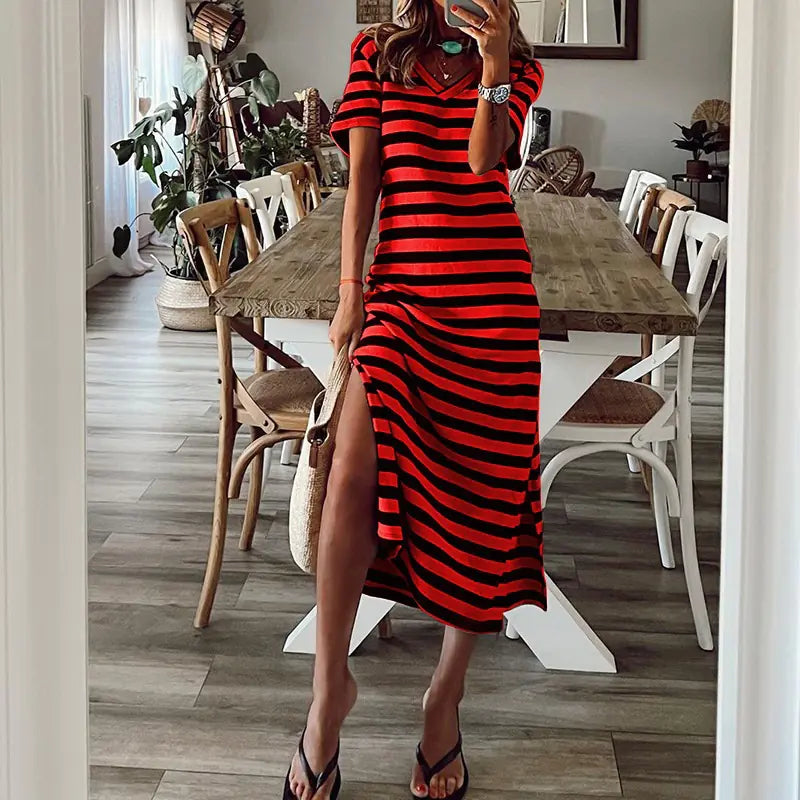 A woman wearing a black and red striped loose V-neck midi dress with a high side slit.