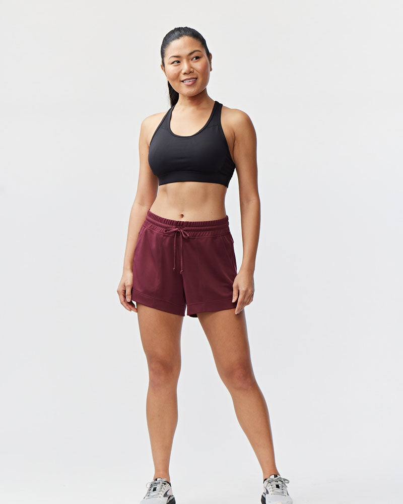 Model wearing dark maroon 4.5 inch knit athletic shorts with a drawstring waist and side pockets