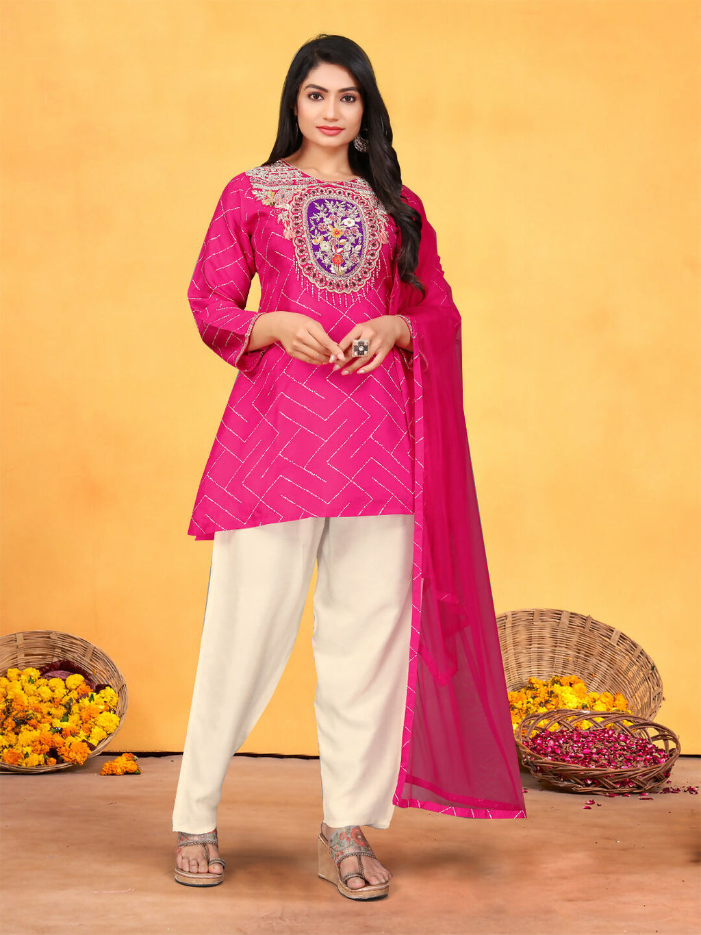 Woman wearing a vibrant rani pink viscose dola kurta set with geometric prints, handwork, and an organza dupatta.