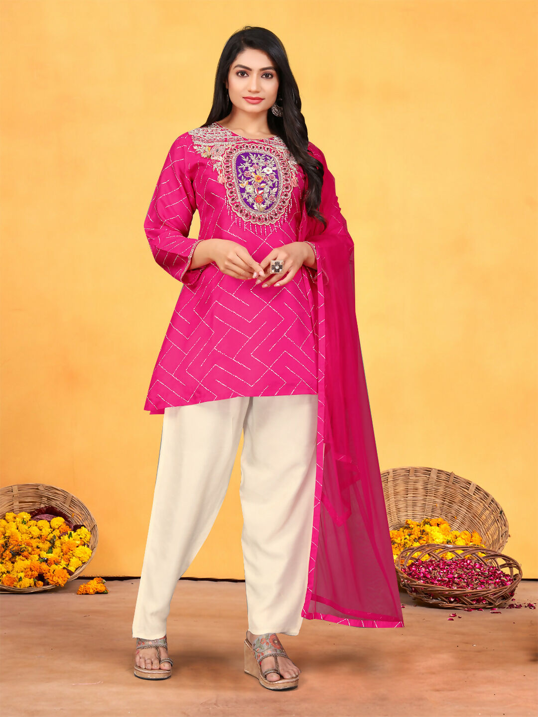 Woman wearing a vibrant rani pink viscose dola kurta set with geometric prints, handwork, and an organza dupatta.
