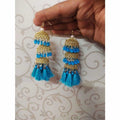 Gold-tone jhumka earrings featuring blue pearls and intricate silk thread work.