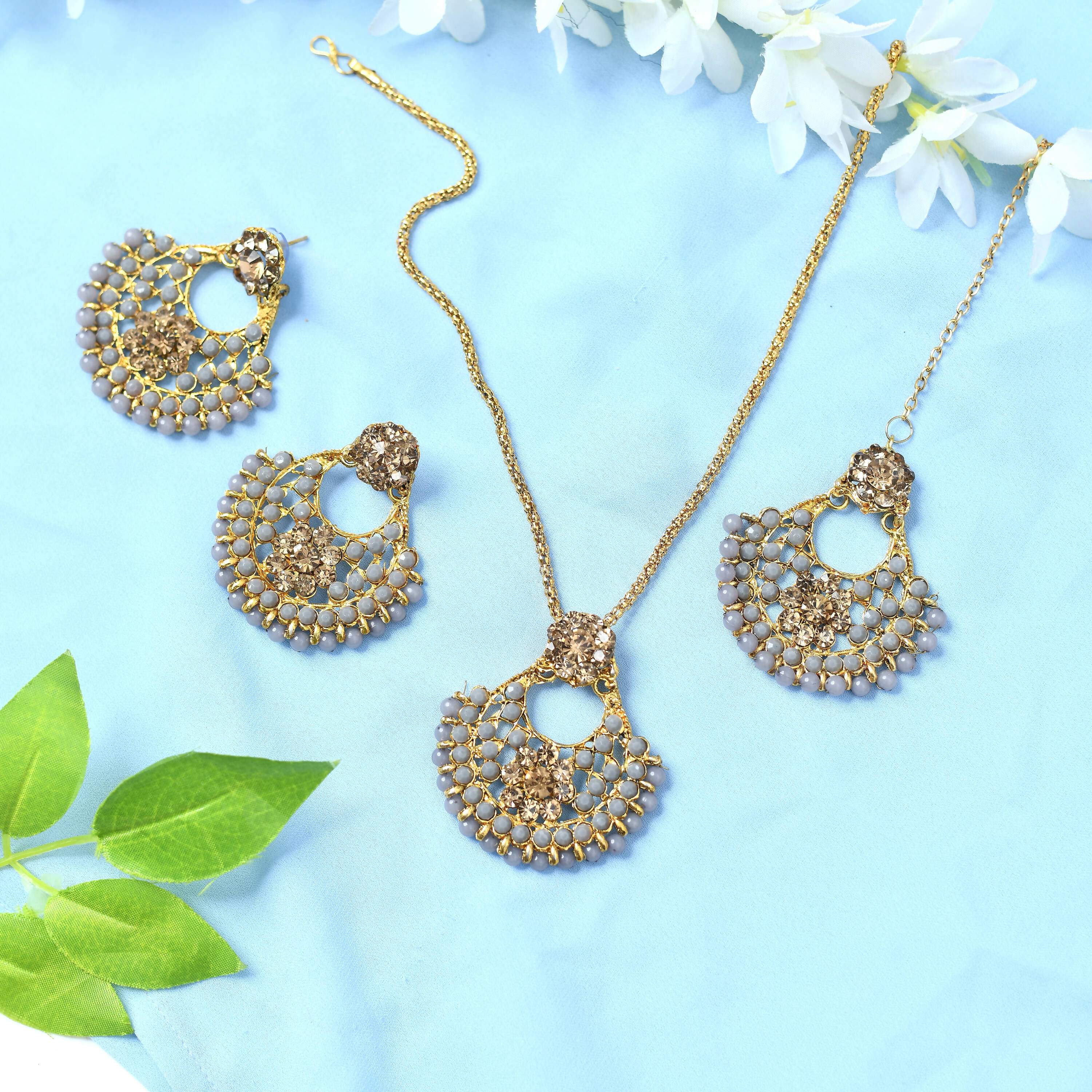 Statement long necklace in gold-polished brass with golden and grey design elements.