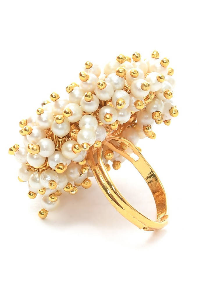Close up of a gold-plated fashion ring featuring white pearls on a neutral background