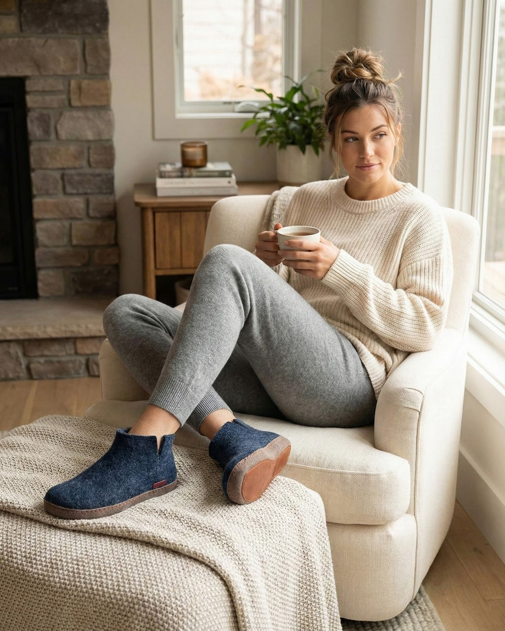 Woman sitting on a couch holding a mug in a cozy living room.