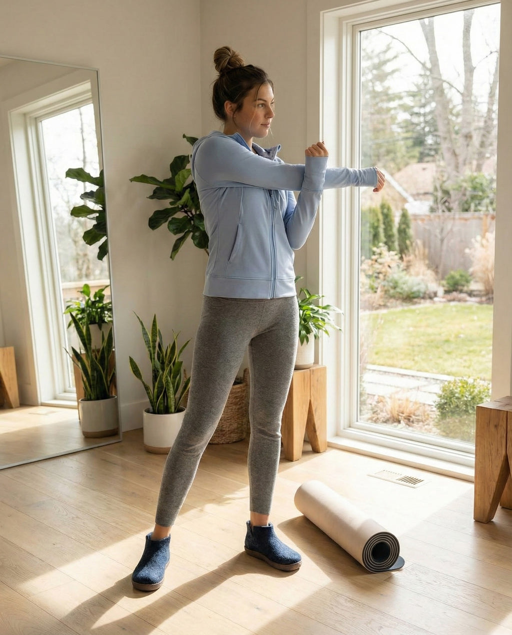 Woman stretching in a bright room with large windows and plants.