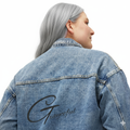 Woman wearing a relaxed fit, medium blue denim jacket with collared neckline and button-down closure
