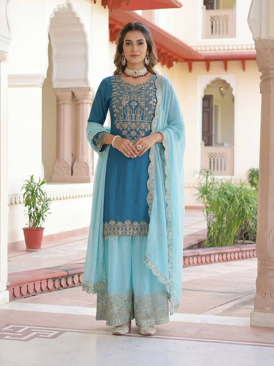 Woman wearing a blue silk embroidered kurti and sharara set with matching dupatta