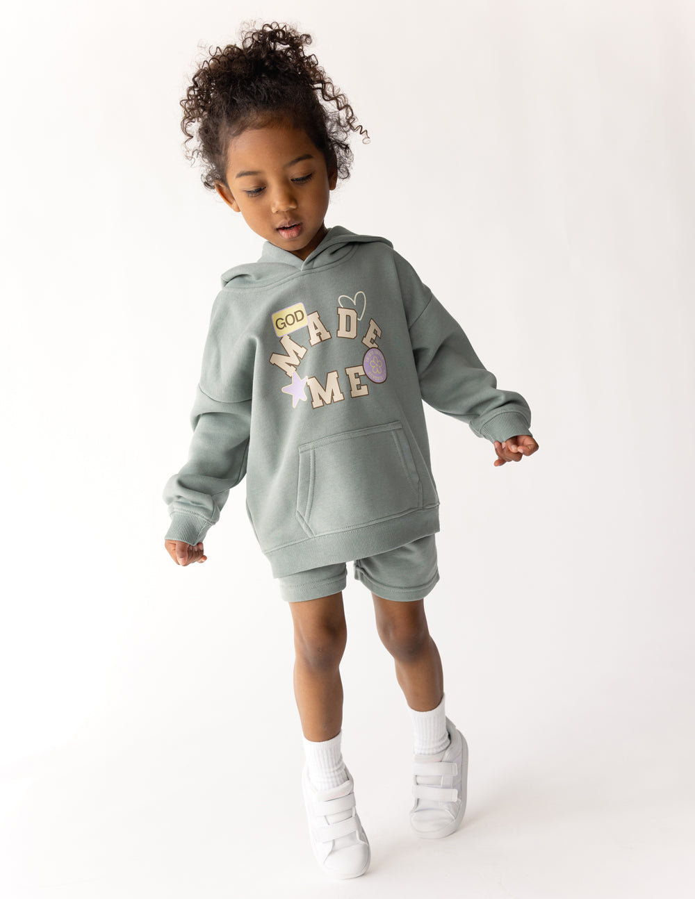 Child wearing a soft, oversized God Made Me hoodie in a casual setting
