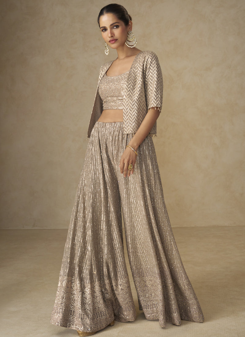 A woman wearing a beige georgette jacket-style co-ord set with intricate embroidery and gota patti hand work.