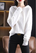 A woman wearing a cozy white hooded long-sleeve cable knit sweater paired with black pants.