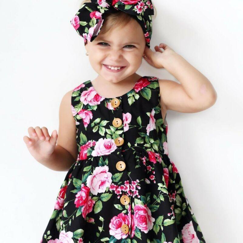 Baby girl wearing a floral summer dress with ruffled sleeves and a bow, including matching headband.