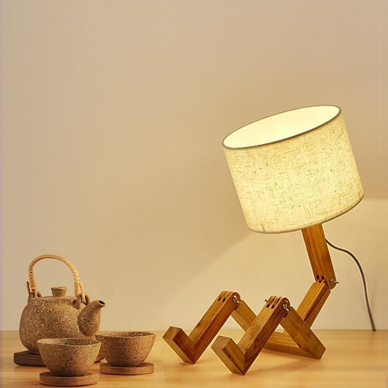 Wooden robot-shaped table lamp with an off-white linen shade and adjustable joints.
