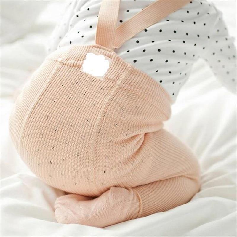 Baby wearing high-waist leggings with unique cross-belt design detailing.