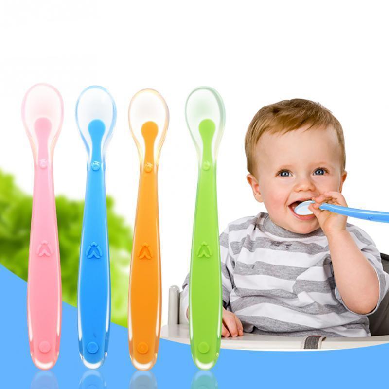 Colorful flexible silicone baby training spoon for self-feeding on a clean surface
