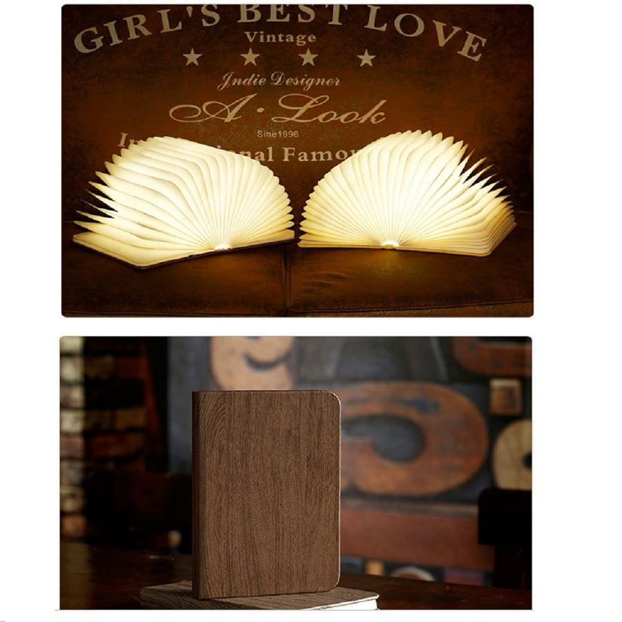 Foldable wooden book lamp in open position emitting a soft, modern glow on a bedside table.