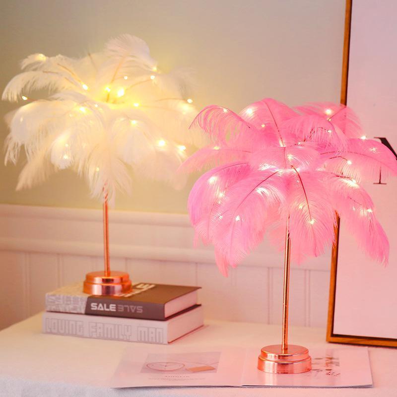 A decorative feather tree LED table lamp glowing in a bedroom.
