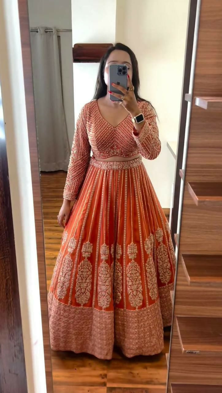 Bright orange faux georgette lehenga choli with sequins and thread embroidery.