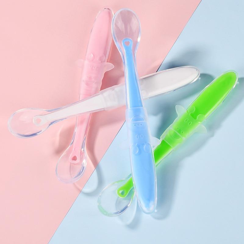 Baby using a soft blue silicone training spoon for self-feeding