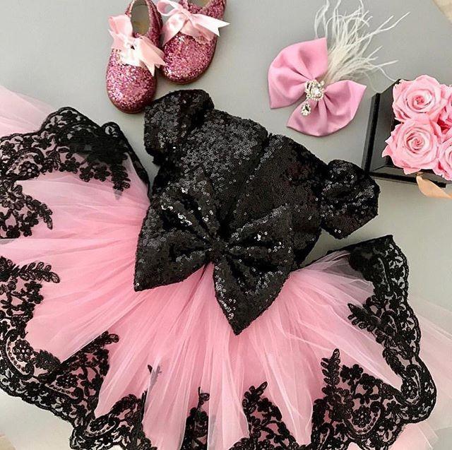 Girl wearing a glamorous A-line formal dress in high-contrast black and pink with cap sleeves.